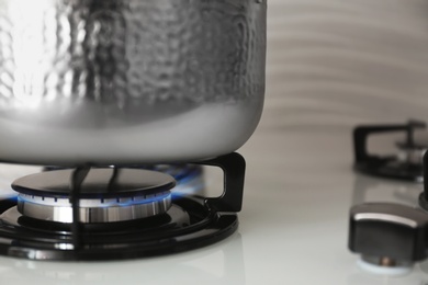 Photo of Shiny steel saucepan on modern gas stove, closeup. Space for text