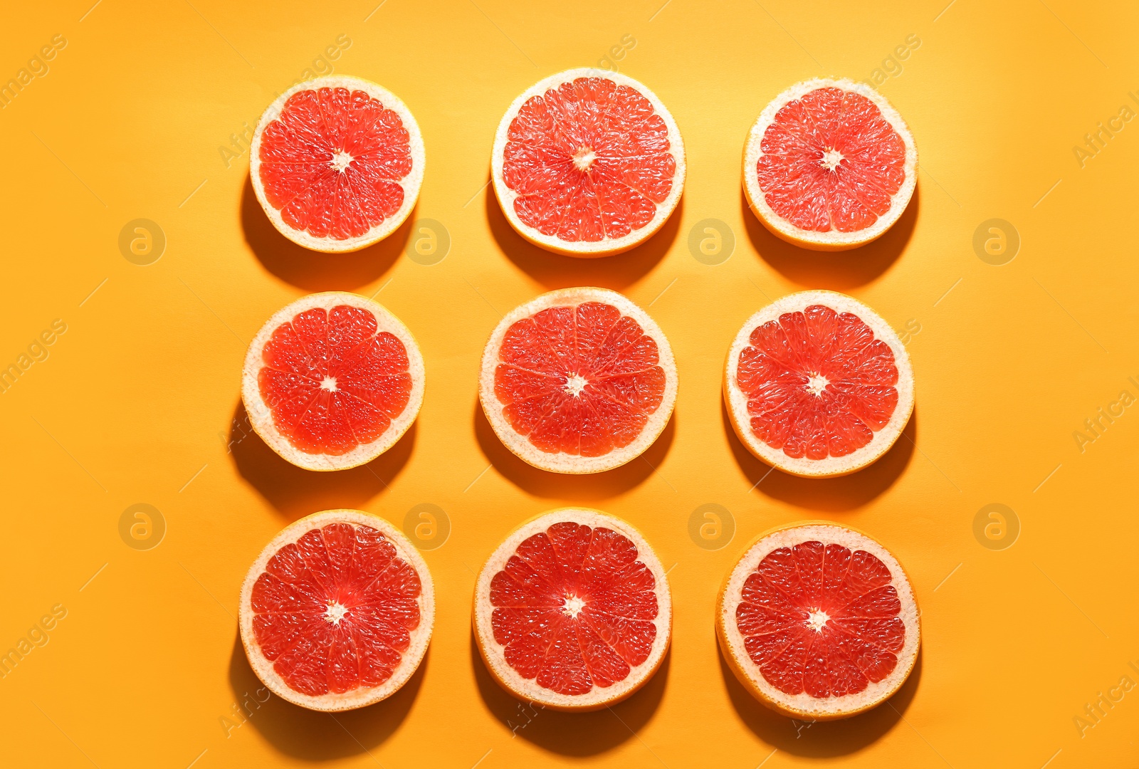 Photo of Flat lay composition with tasty ripe grapefruit slices on orange background