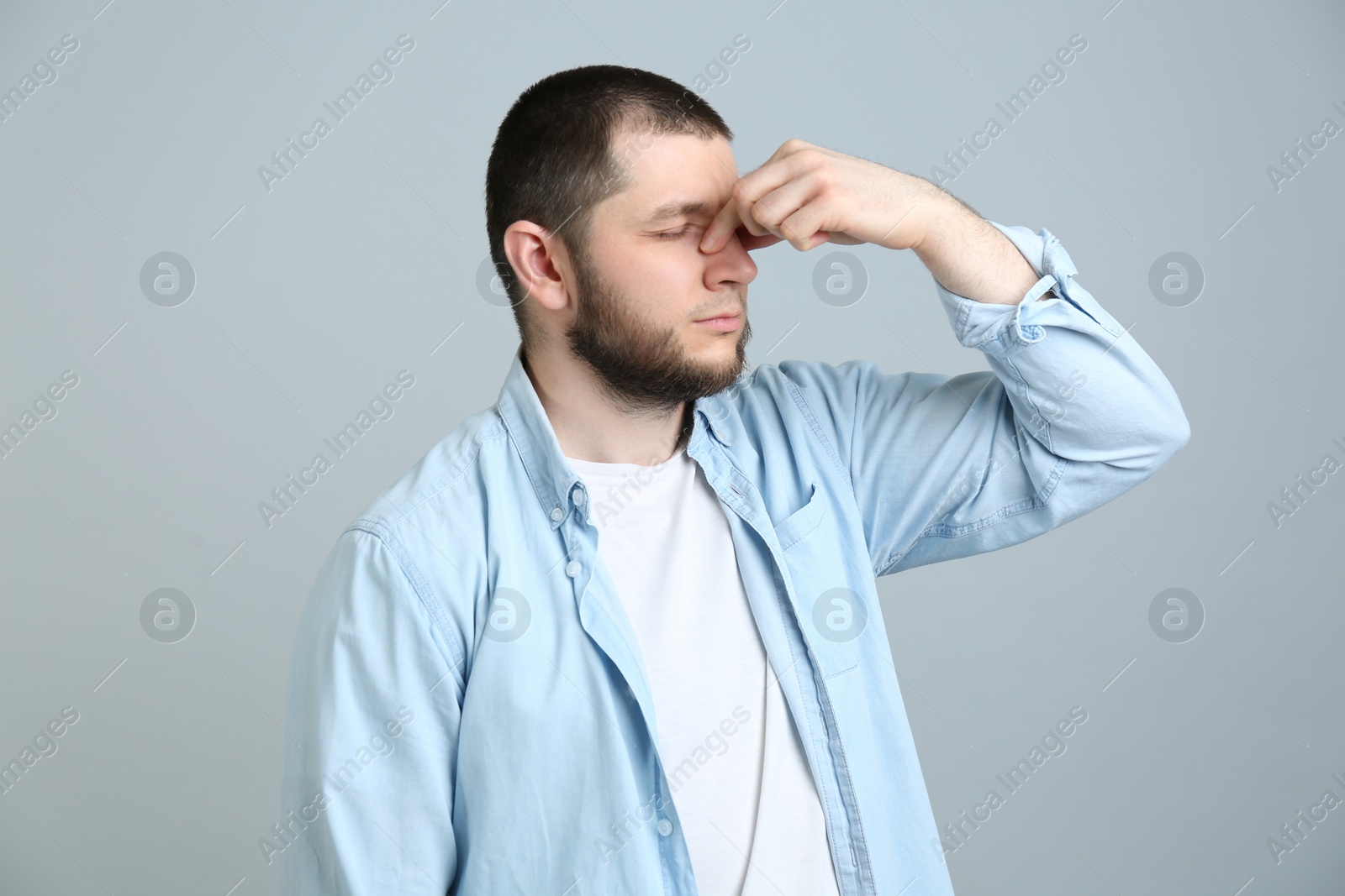 Photo of Man suffering from runny nose on light grey background