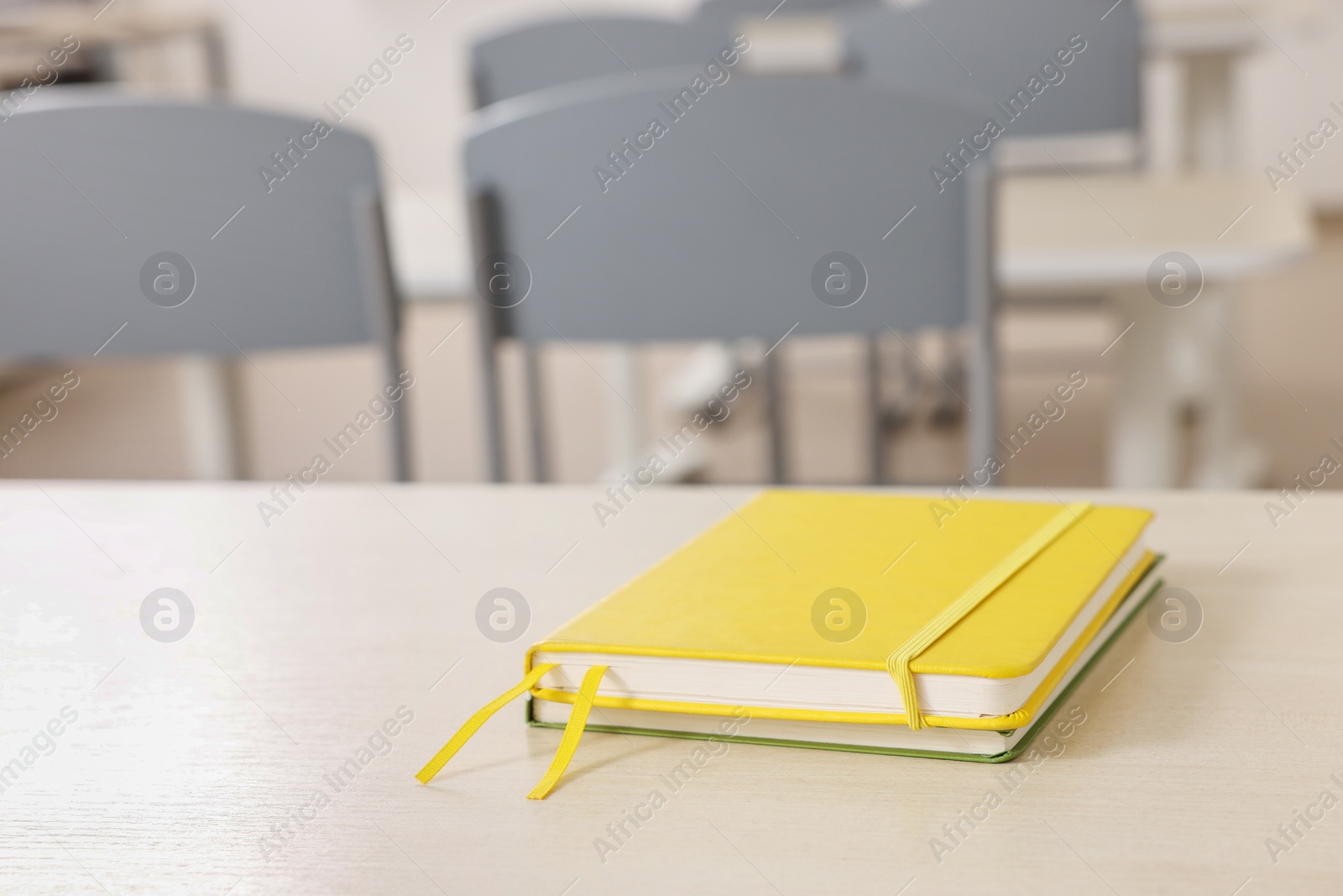 Photo of Notebooks on wooden desk in empty classroom