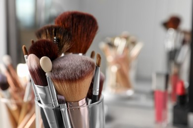 Set of professional brushes and makeup products near mirror, closeup. Space for text