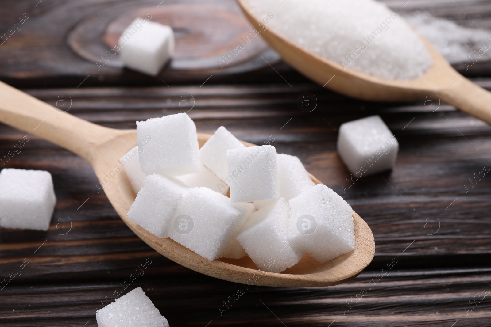 Photo of Spoons with different types of white sugar on wooden table, closeup