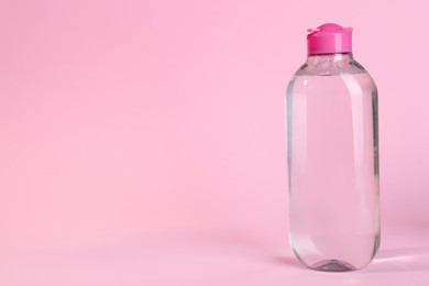 Photo of Bottle of micellar water on pink background. Space for text