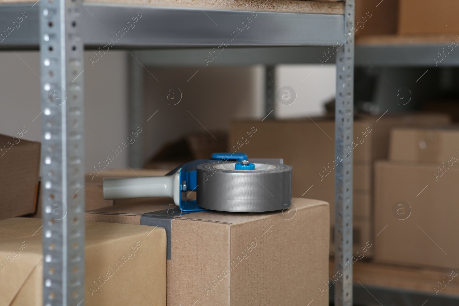 Photo of Adhesive tape dispenser on cardboard box indoors