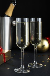 Photo of Happy New Year! Glasses with sparkling wine on table against black background