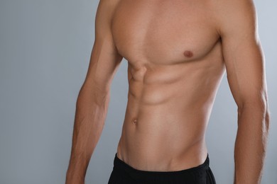 Shirtless man with slim body on grey background, closeup