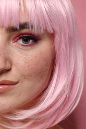 Photo of Beautiful woman with bright makeup and fake freckles on pink background, closeup