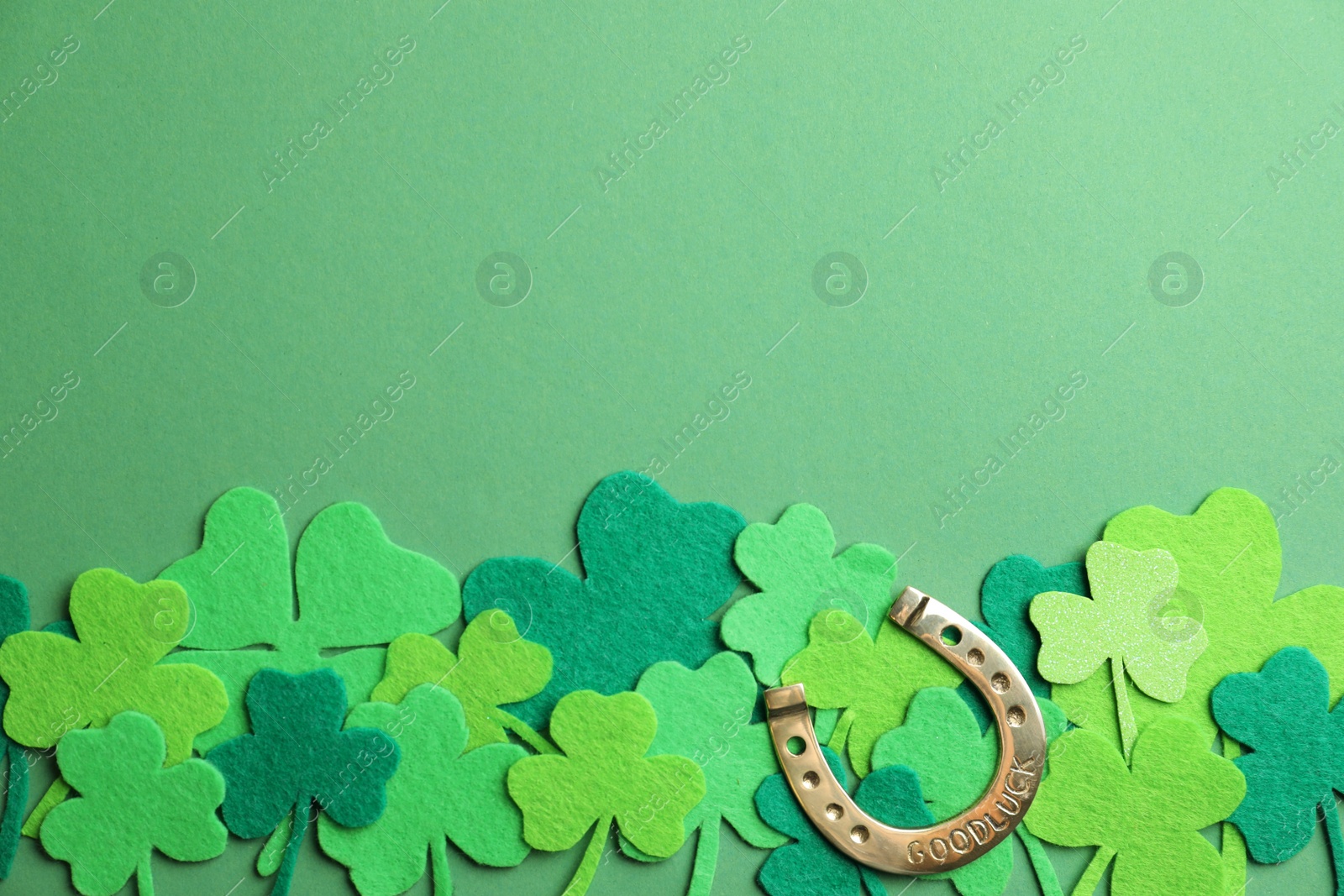 Photo of Flat lay composition with clover leaves and horseshoe on green background, space for text. St. Patrick's day