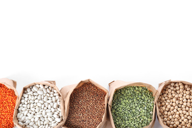 Photo of Different types of legumes  and cereals in paper bags on white background, top view. Organic grains