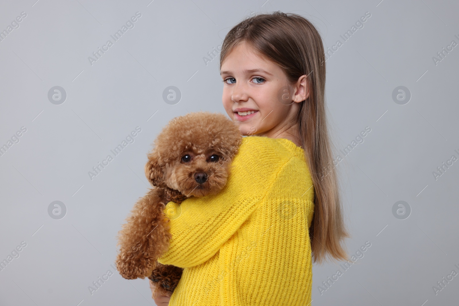 Photo of Little child with cute puppy on light grey background. Lovely pet