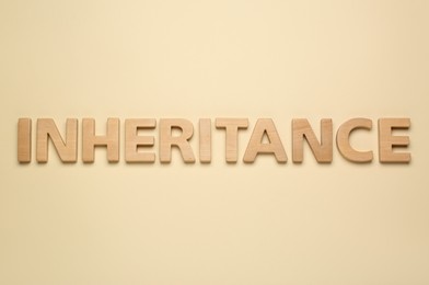 Word Inheritance made with wooden letters on beige background, flat lay