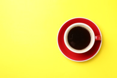 Photo of Aromatic coffee in cup on yellow background, top view. Space for text