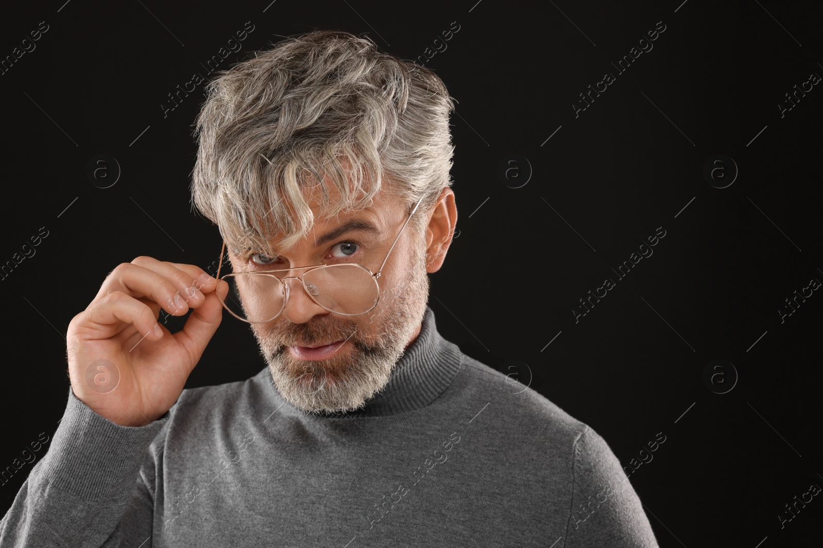 Photo of Portrait of confident man with beautiful hairstyle on black background. Space for text