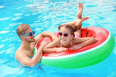 Photo of Young man with daughter in pool on sunny day