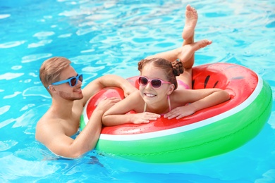 Young man with daughter in pool on sunny day