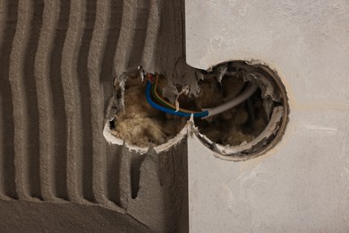 Photo of Adhesive mix, tile and socket hole with wires on wall, closeup. Space for text