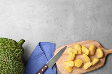 Photo of Delicious exotic jackfruit and bulbs on light grey table, flat lay. Space for text