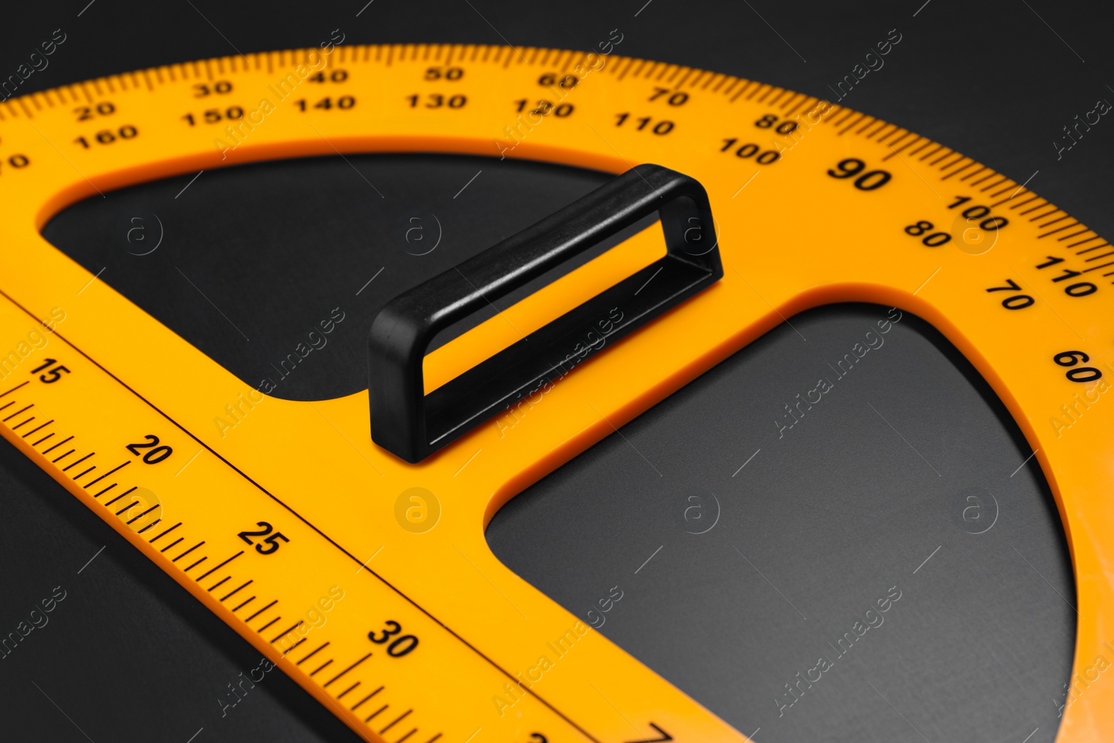 Photo of Yellow school protractor on blackboard, closeup view