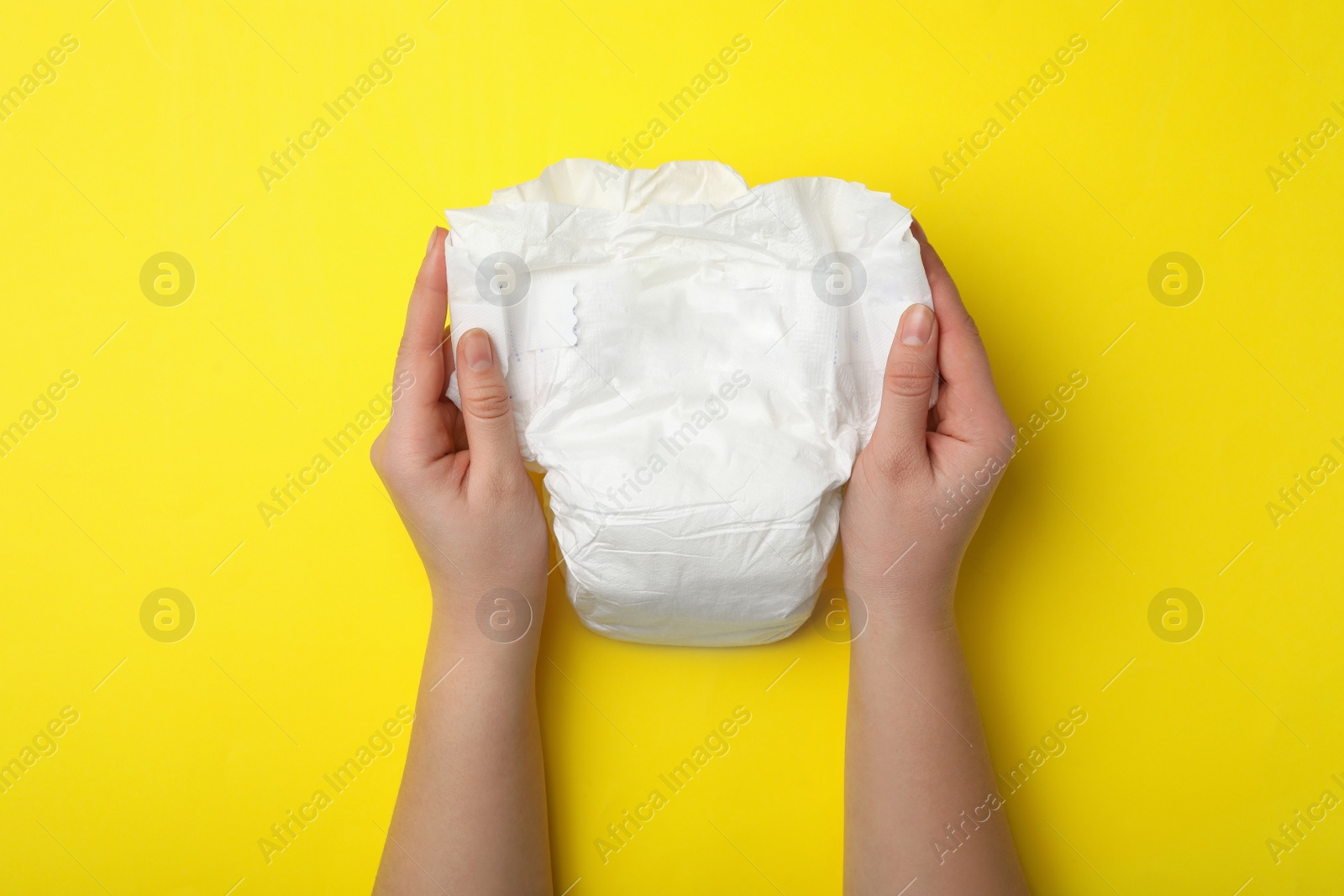 Photo of Woman with diaper on yellow background, closeup