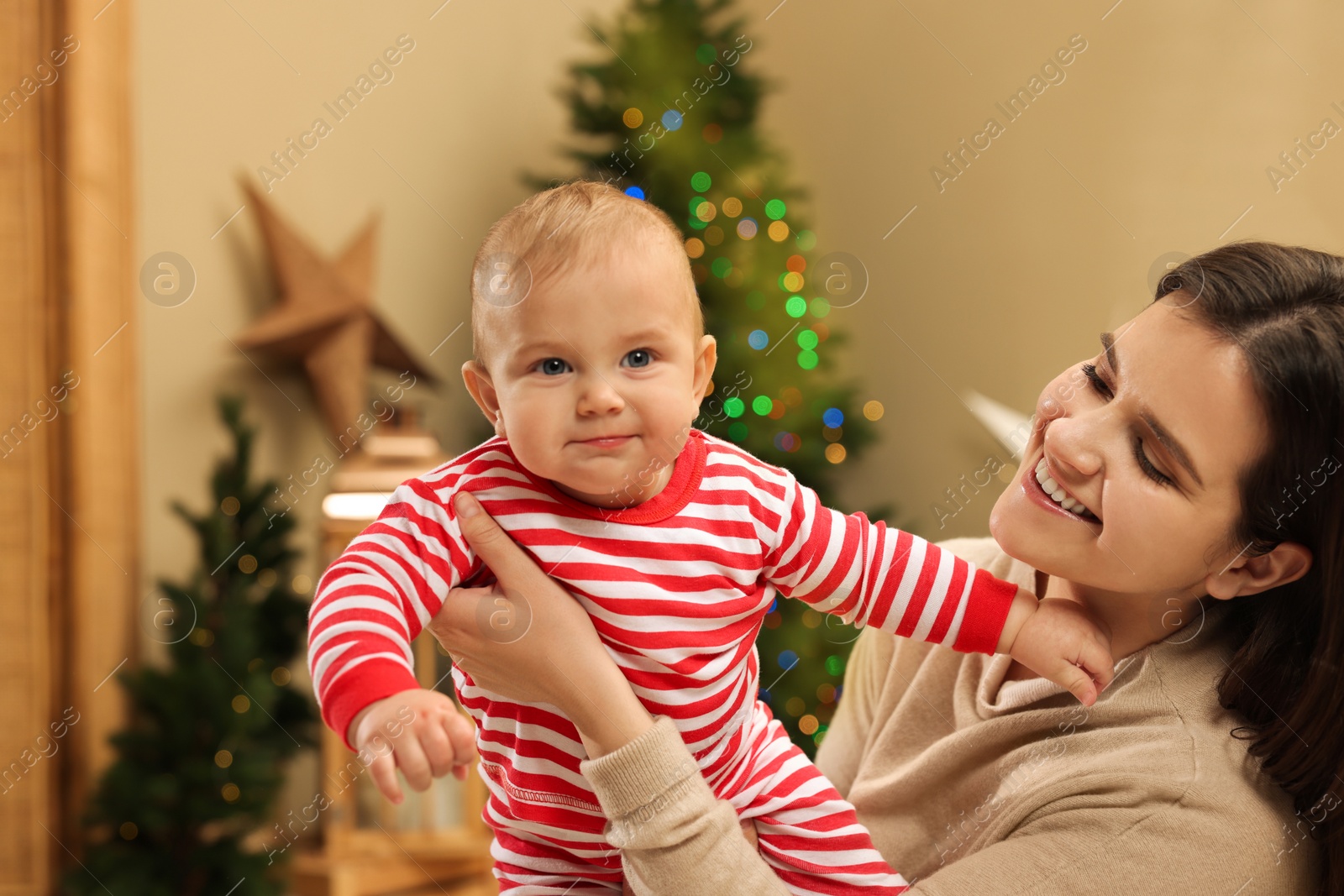 Photo of Happy you mother with her cute baby in room decorated for Christmas. Winter holiday