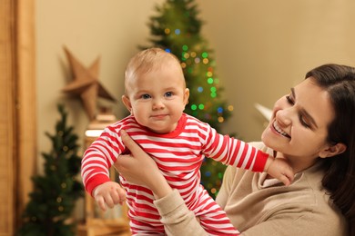 Happy you mother with her cute baby in room decorated for Christmas. Winter holiday