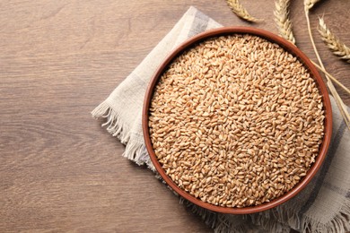 Photo of Wheat grains and spikes on wooden table, flat lay. Space for text