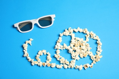 Photo of Reel made of popcorn and glasses on color background, top view. Cinema snack