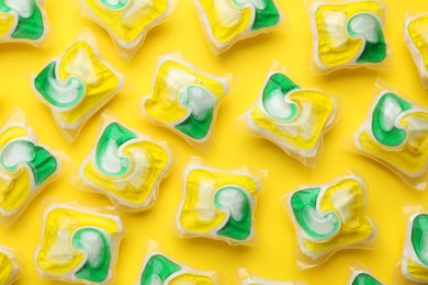 Photo of Many dishwasher detergent pods on yellow background, flat lay