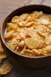Photo of Tasty cornflakes with milk in bowl on wooden table, closeup