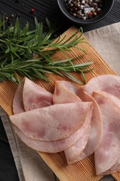 Photo of Slices of delicious ham with rosemary and spices on dark wooden table, flat lay