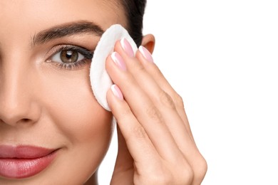 Beautiful woman removing makeup with cotton pad on white background, closeup