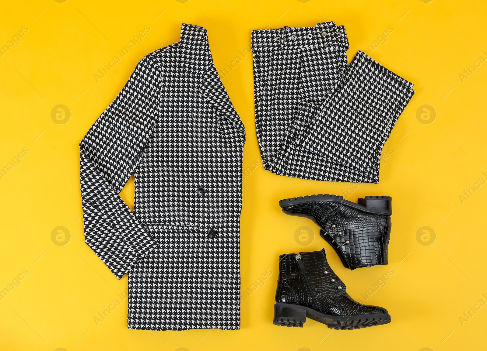 Photo of Stylish ankle boots and office suit on yellow background, flat lay
