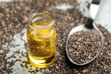 Photo of Bottle of oil, spoon and chia seeds on table, closeup. Space for text