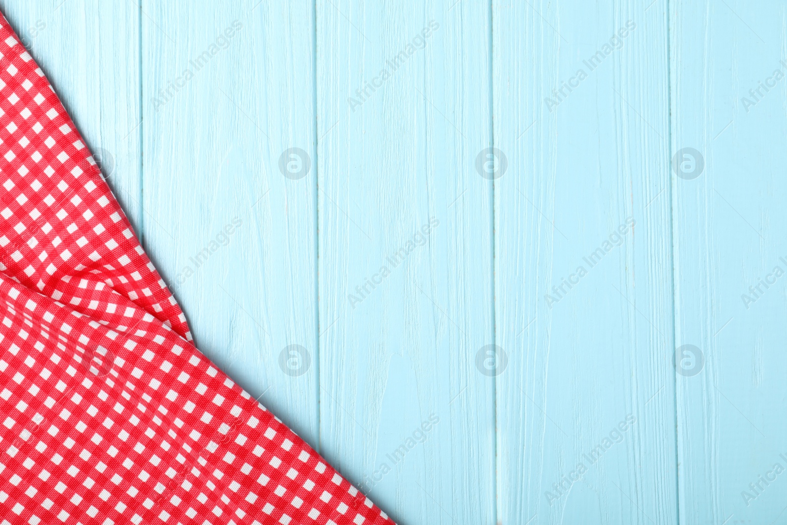 Photo of Checkered picnic blanket on wooden background, top view. Space for text