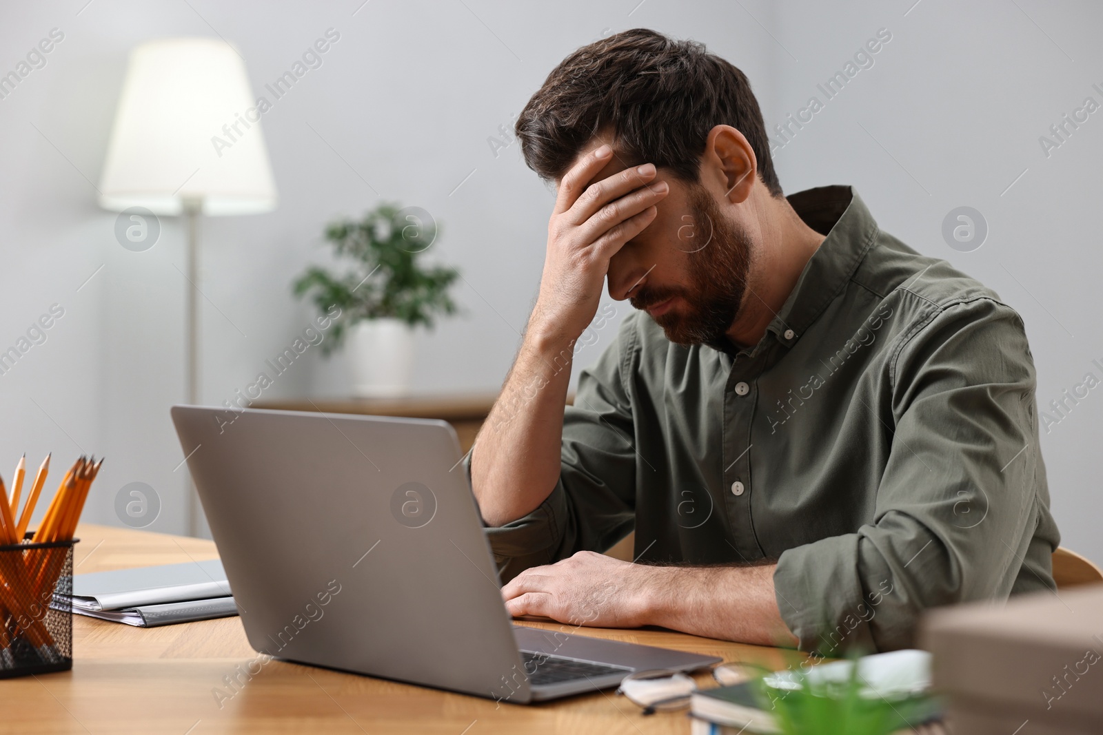 Photo of Tired man suffering from headache at workplace