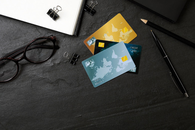 Photo of Credit cards and stationery on black background, flat lay
