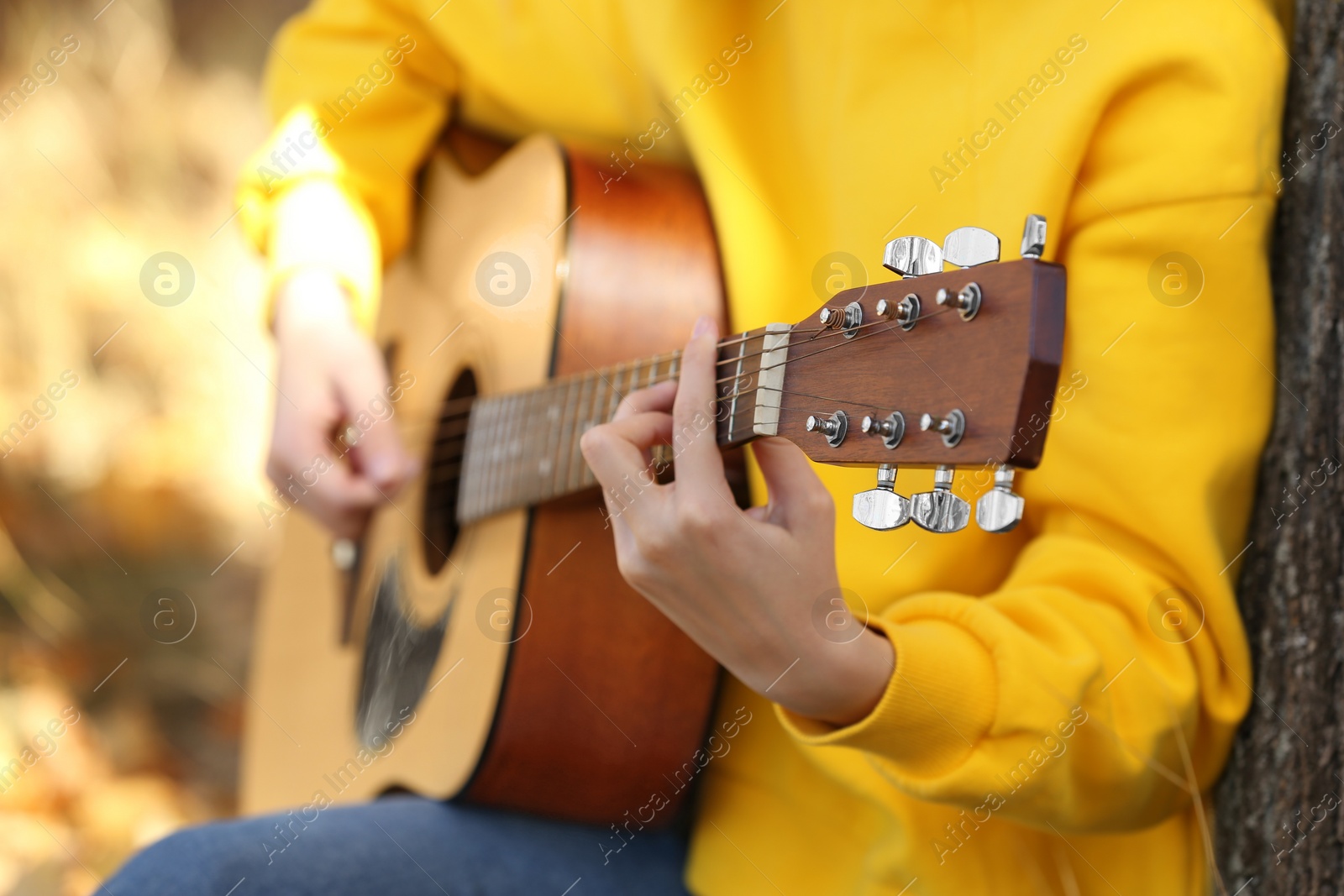 Photo of Teen girl playing guitar in autumn park, closeup