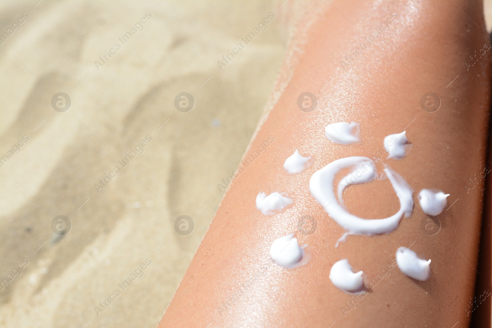 Photo of Sun drawn with sunscreen on woman's leg at beach, closeup. Space for text