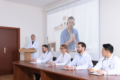 Image of Lecture with online participant. Doctors in meeting room. Using projector for videoconference