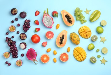 Many different delicious exotic fruits on light blue background, flat lay