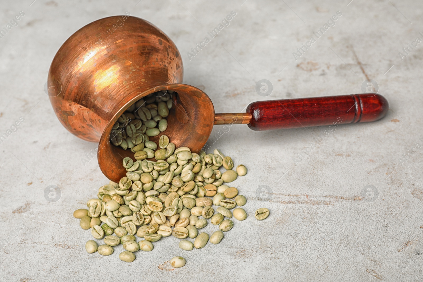 Photo of Overturned jezve with green coffee beans on grey background