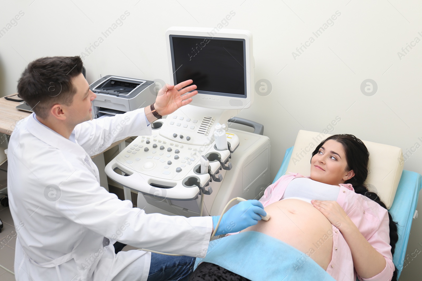 Photo of Young pregnant woman undergoing ultrasound scan in clinic