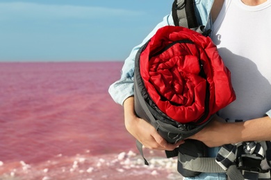 Woman with sleeping bag on coast of pink lake