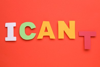 Photo of Motivation concept. Changing phrase from I Can't into I Can by removing paper letter T on red background, top view