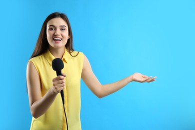 Photo of Young female journalist with microphone on blue background