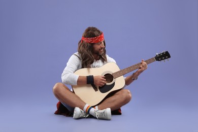 Photo of Stylish hippie man playing guitar on violet background