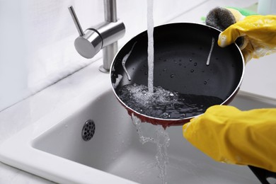 Photo of Woman washing frying pan with sponge in kitchen sink, closeup