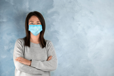 Woman with disposable mask on face against light blue background. Space for text