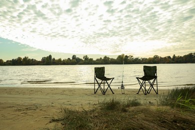 Photo of Folding chairs and fishing rod at riverside, space for text