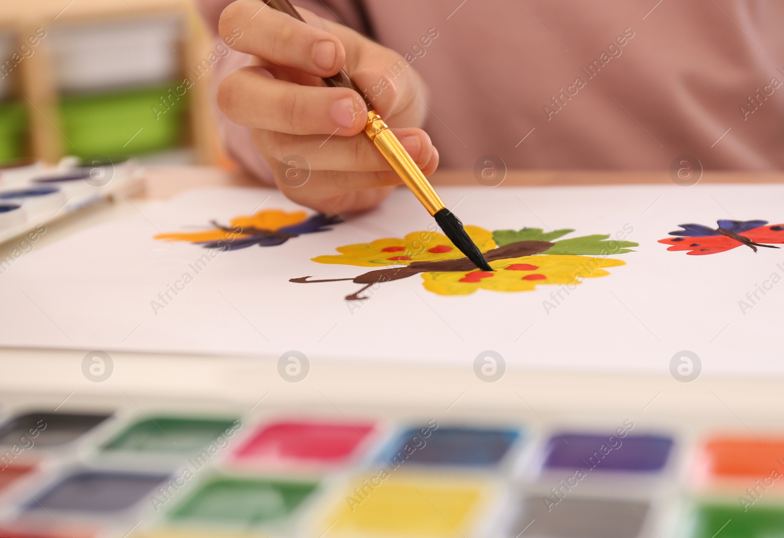 Photo of Little child painting butterfly at table, closeup